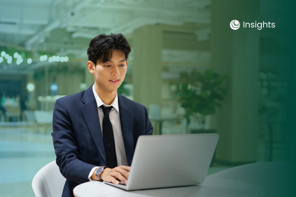 A suited man works intently on a laptop at a table, conveying a business environment.