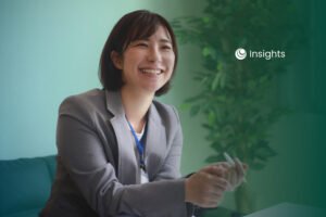 A smiling Asian professional woman in a grey suit jacket holding a pen, with an "Insights" logo in the background.