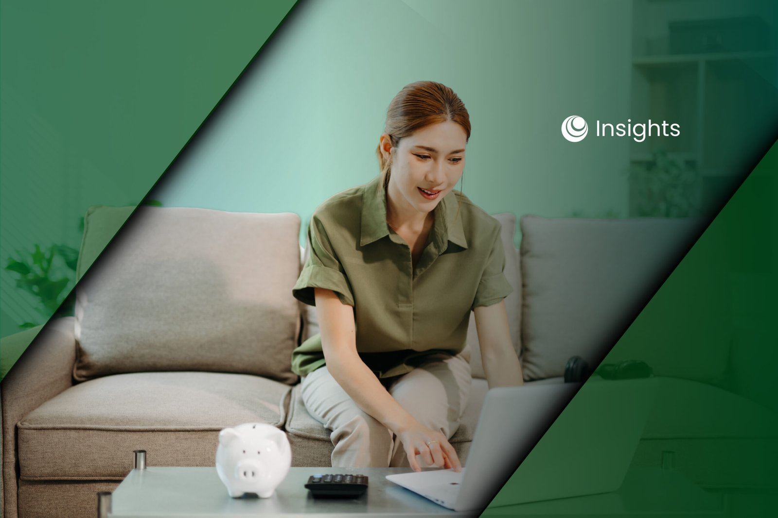 A woman sitting on a sofa and using a laptop, with a piggy bank and calculator on the coffee table in front of her.
