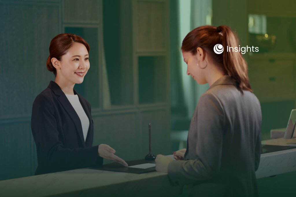 A smiling receptionist assisting a customer at a front desk or reception counter.